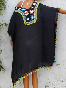 Detail of colorful crochet floral neckline and vibrant fringe on black beach cover-up