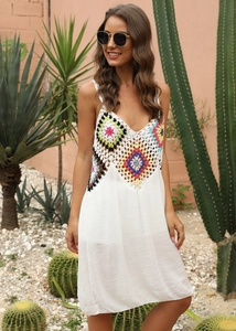 Détail du corsage en patchwork de crochet multicolore sur une robe longue de plage blanche