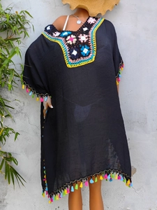 Detail of colorful crochet neckline and vibrant fringe on a black beach cover-up dress