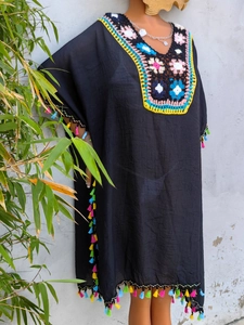 Close-up of bohemian black kaftan with colorful handmade crochet collar and fringe details