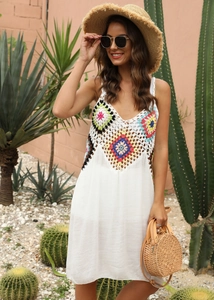 Détail des motifs crochet bohème colorés sur une robe de plage blanche à bretelles