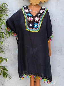 Detailed crochet floral collar and colorful tassel trim on a black bohemian beach dress