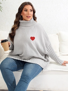 Close-up of oversized grey knit turtleneck sweater featuring a red heart embroidery