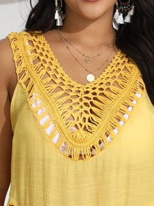 Detailed close-up of vibrant yellow crochet neckline and textured fabric on the beach dress
