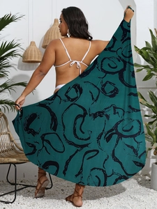 Detail of dark teal beach cover-up with black abstract circular patterns and fringe edges