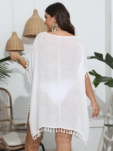 Close-up of white bohemian beach cover-up featuring textured fabric and tassel details