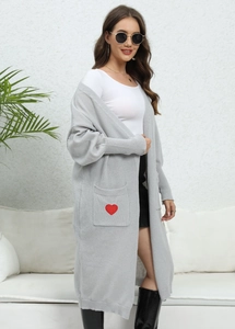 Detail shot of a soft grey knit cardigan featuring red heart embroidery on the pocket