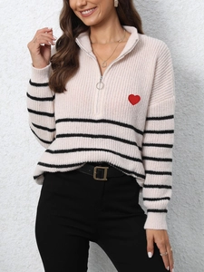 Detail of knit sweater showing half-zip collar, stripes, and red heart embroidery