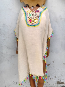 Detail of colorful crochet neckline and multi-color fringe on beige beach cover-up dress