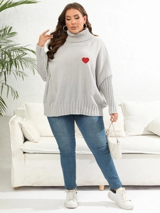Close-up detail of oversized grey knit sweater with red heart embroidery patch
