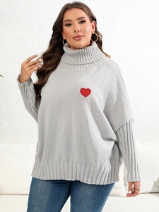 Detailed close-up of red heart embroidery on gray high neck knitted sweater