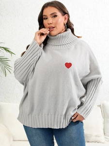 Detail of red heart patch on grey oversized high neck knit sweater for women