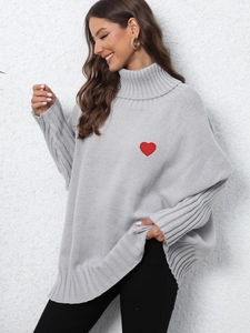 Detail of red heart embroidery and ribbed cuffs on grey turtleneck knit sweater