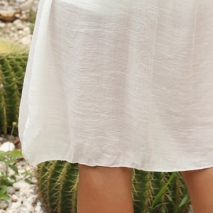 Détail de l'ourlet de la robe au crochet blanc montrant la texture tissée du tissu
