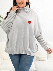 Detail of grey oversized turtleneck sweater featuring a red heart embroidery patch