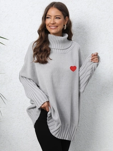 Close-up of light grey turtleneck sweater featuring a red heart embroidery patch
