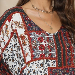 Macro detail of V-neckline on bohemian ethnic print maxi dress with gold layered necklaces