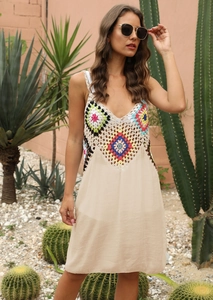Détail du patchwork au crochet boho et du tissu tissé beige sur une robe de plage