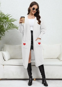 Detailed knit texture of white long cardigan featuring red heart patches on pockets