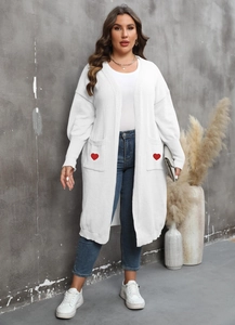 Detail of white knit cardigan showing large front pockets with red heart embroidery
