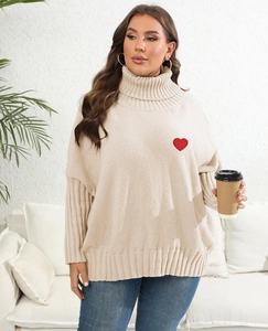 Close-up of a beige high-neck sweater featuring a red heart embroidery on the chest
