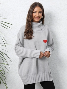 Detail of grey knit sweater featuring a red heart embroidery and turtleneck design