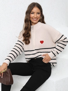 Detailed close-up of knit texture with red heart embroidery and silver ring zipper