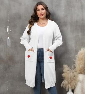 Detail of white longline cardigan featuring ribbed cuffs and red heart patch pockets
