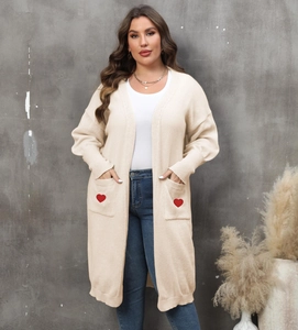 Detail view of long knit cardigan featuring large pockets with red heart embroidery