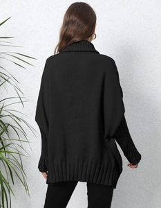 Detail view of black oversized knit sweater featuring turtleneck and ribbed hem on model back