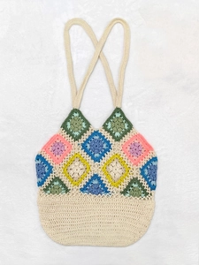 Handmade crochet granny square shoulder bag with colorful floral patterns on beige yarn