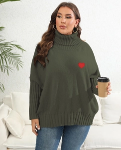 Detail shot of green chunky knit sweater with red heart embroidery and turtleneck
