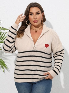 Détail du col zippé avec anneau argenté sur un pull à rayures et cœur rouge