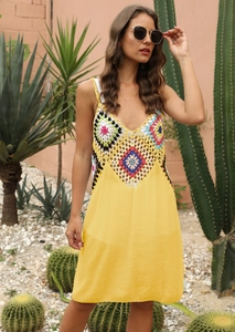 Détail du corsage en crochet bohème avec des motifs floraux colorés sur une robe de plage