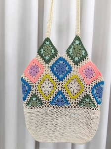 Handmade crochet granny square tote bag with colorful floral patterns and white straps