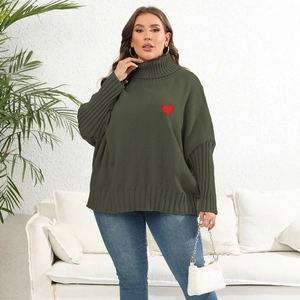 Detail of the oversized dark green knitted sweater featuring a red heart embroidery
