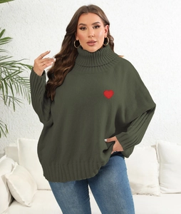Detail of red heart embroidery on the chest of a loose olive green knit sweater