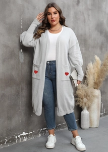 Detail of grey knitted cardigan showing functional pockets and red heart embroidery patches