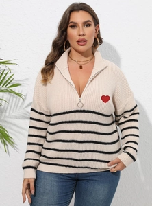 Détail du patch cœur rouge sur un pull en maille rayée avec zip et anneau argenté