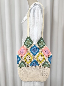 Macro view of handmade granny square crochet tote bag with colorful floral patchwork patterns