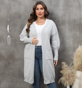 Détail des poignets côtelés et des grandes poches carrées sur un long gilet gris tricoté