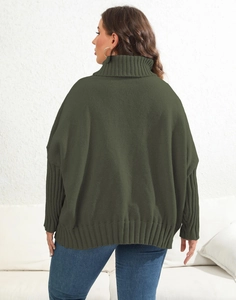 Close-up of chunky knit texture and ribbed cuffs on a dark green oversized sweater