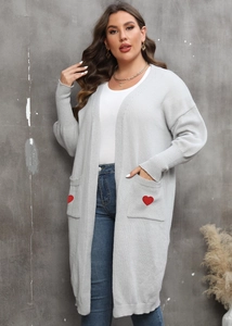 Detail of red heart patch on a long light grey knit cardigan with large side pocket