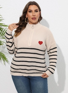 Détail du pull à rayures beige avec écusson cœur rouge et fermeture éclair à anneau