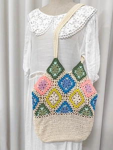Detail of colorful crochet patchwork pattern and wide shoulder strap of the handbag