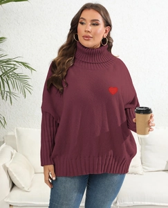 Close-up of oversized burgundy knit sweater with a red heart applique and thick texture