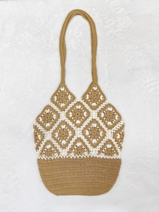 Detailed macro shot of khaki crochet texture and geometric diamond pattern on tote bag