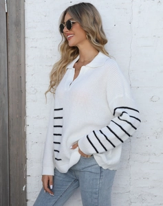 Close-up of a cream polo neck sweater featuring black stripes and a V-neck knitted texture