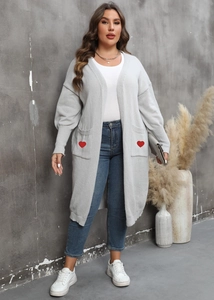 Detailed view of long grey knit cardigan featuring red heart embroidery on front pockets