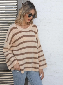 Detail of color-block striped knit sweater featuring button accents and loose-fit texture